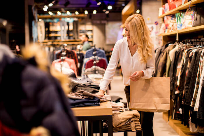 young-woman-with-shopping-bags-standing-clothing-store